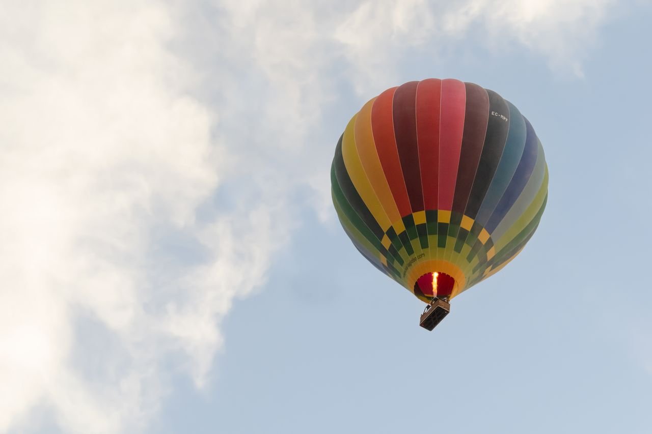 Colorful hot air balloon soaring amidst clouds in Valladolid, Spain.